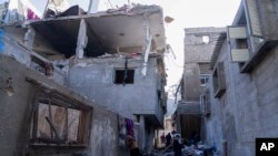 팔레스타인인들이 3일 가자지구 칸 유니스 마을에 대한 이스라엘의 공습으로 파손된 건물을 점검하고 있다.
