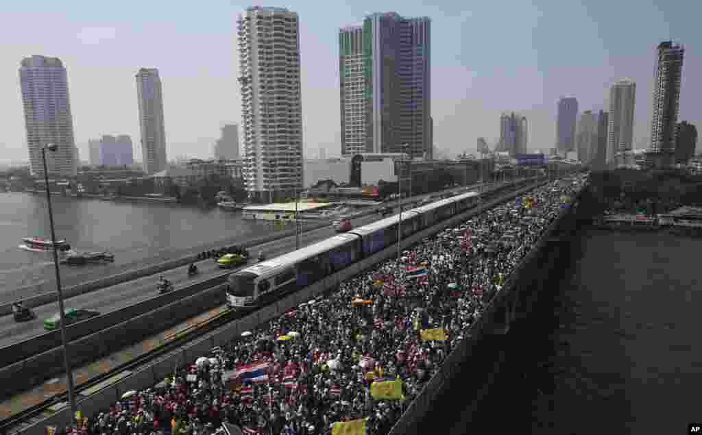 Thai anti-government protesters march cross Takin Bridge during a rally, Dec. 22, 2013, in Bangkok, Thailand.&nbsp;
