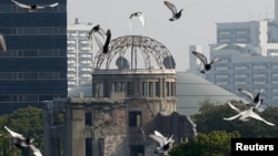 FILE - Doves fly over Peace Memorial Park with the Atomic Bomb Dome in the background, at a ceremony in Hiroshima, Japan, Aug. 6, 2015. 