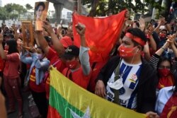 Myanmar migrants hold up portraits of detained leader Aung San Suu Kyi as they rally outside Myanmar's embassy in Bangkok, Thailand, Feb. 1, 2021.