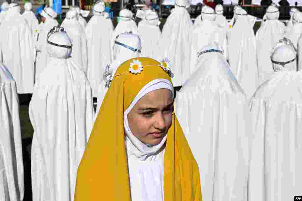 Iraqi Muslim girls, who traditionally begin wearing the hijab, a head covering worn in public at the mandatory age of nine, take part in a ceremony organized at a stadium in Basra.