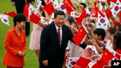 Chinese President Xi Jinping, right, and South Korean President Park Geun-hye, left, greet children at the Presidential Blue House in Seoul, South Korea, July 3, 2014.