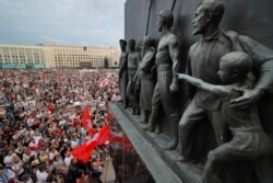 FILE - Belarusian opposition supporters gather for a protest rally in front of the government building at Independent Square in Minsk, Belarus, with Soviet-era sculptures in the foreground, Aug. 18, 2020.
