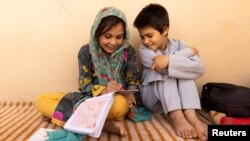 Samira, 9, and Aminullah help each other with homework at the orphanage in Kabul, Afghanistan, October 10, 2021. (REUTERS/Jorge Silva)