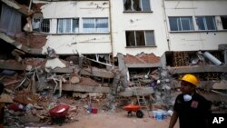 A rescue worker walks in front of an apartment building whose first four floors collapsed, in the Lindavista neighborhood of Mexico City, Sept. 20, 2017. 