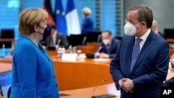 German Chancellor Angela Merkel, left, and the chairman of the German Christian Democrats, Armin Laschet, right speak as they arrive for a virtual Plenary Session of the Franco-German Council of Ministers in Berlin, Germany, May 31, 2021. 