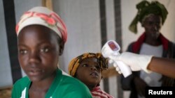 FILE - A health worker checks the temperature of a girl at the entrance to a Red Cross facility in the town of Koidu, Sierra Leone.