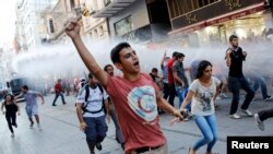 Demonstran anti-pemerintah berlarian menghindari semprotan meriam air yang ditembakkan oleh polisi anti huru-hara di jalan utama Istiklal di pusat kota Istanbul (3/8).