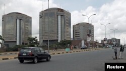 Petrol hawkers are seen standing in front of the corporate headquarters of the Nigeria National Petroleum Corporation in Abuja, Nigeria, July 13, 2015.