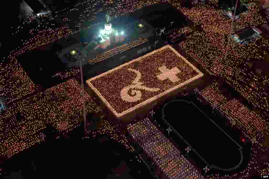 People and nurses from a hospital light candles in formation of Thai script showing numbers representing the late Thai King Bhumibol Adulyadej (L) at a park in Bangkok, Thailand.