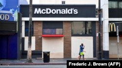 Seorang pejalan kaki berjalan melewati gerai makanan cepat saji McDonald's yang ditutup sementara karena pandemi COVID-19 di Hollywood Boulevard, California, pada 15 Oktober 2020. (Foto: AFP/Frederic J. Brown)