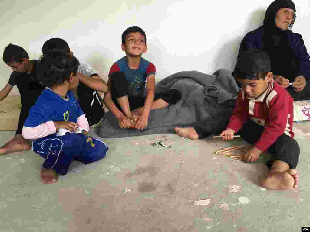 Iraqi refugee children who fled IS with their families playing on the concrete floor of their new home in a camp outside Makhmour, Iraq, April 11, 2016. (S. Behn/VOA)