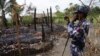 FILE - A Myanmar border guard police officer takes pictures at the remains of a burned house in Tin May village, northern Rakhine state, Myanmar.