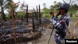 FILE - A Myanmar border guard police officer takes pictures of the remains of a burned down house in Tin May village, northern Rakhine state, Myanmar, July 13, 2017.