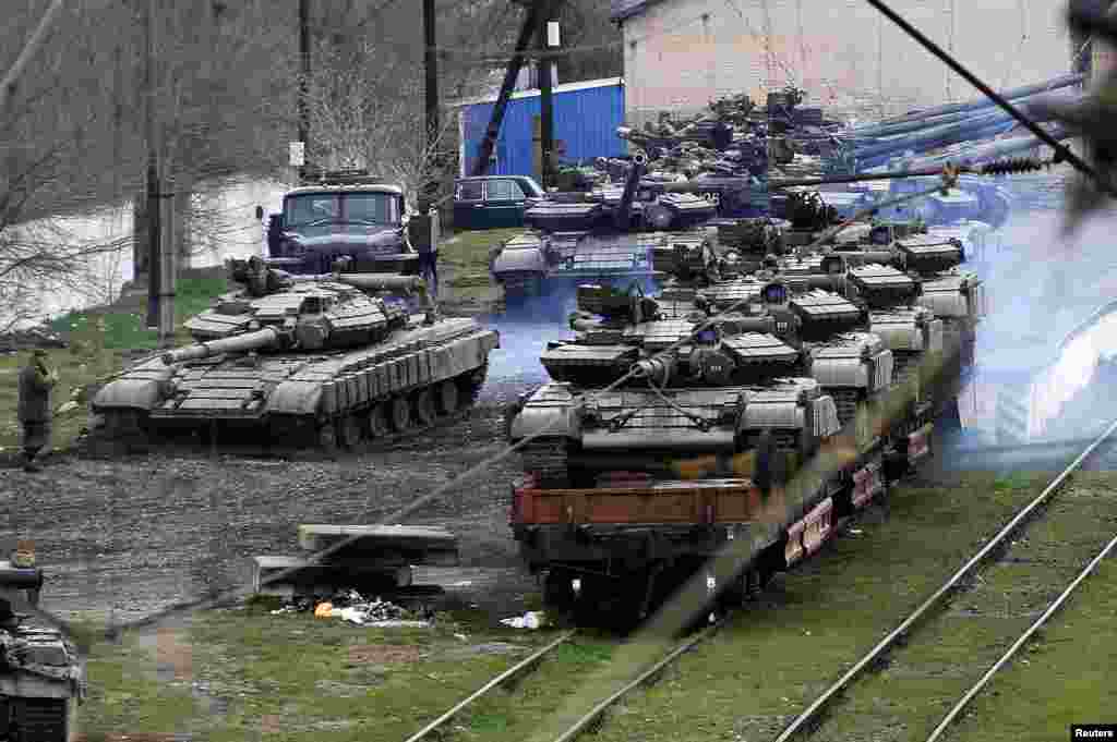 A Russian soldier (L) guides a Ukranian tank which will be loaded onto a train in northern Crimea.