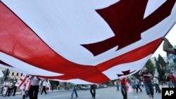 FILE - Georgians carry a giant national flag during a 2008 demonstration in Tbilisi, Georgia.