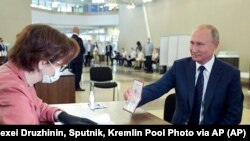 ប្រធានាធិបតីរុស្ស៊ីលោក Vladimir Putin បង្ហាញលិខិតឆ្លងដែនទៅកាន់មន្រ្តីគណៈកម្មការរៀបចំការបោះឆ្នោត នៅមណ្ឌលបោះឆ្នោតមួយ ក្នុងក្រុងមូស្គូ ប្រទេសរុស្ស៊ី កាលពីថ្ងៃទី០១ ខែកក្កដា ឆ្នាំ២០២០។