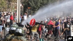 Demonstrators, some wearing protective face masks amid the new coronavirus pandemic, clash with the police during a protest demanding food aid from the government, at a poor neighborhood in Santiago, Chile, May 18, 2020.