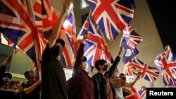 Demonstran anti-pemerintah mengibarkan bendera Inggris, Union Jack, saat demo di depan Konsulat Inggris di Hong Kong, 23 Oktober 2019. (Foto: Umit Bektas/Reuters)