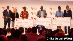 Dr. Conrad Tankou, Rachel Sibande and Dr. Abdoulaye Diallo stand on the stage at NEF holding the $25,000 checks that they won for their innovation prizes.
