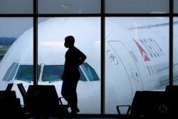 FILE - In this Feb. 18, 2021 file photo, a passenger wears a face mask to help prevent the spread of the new coronavirus as he waits for a Delta Airlines flight at Hartsfield-Jackson International Airport in Atlanta. Airlines have reported about 3…