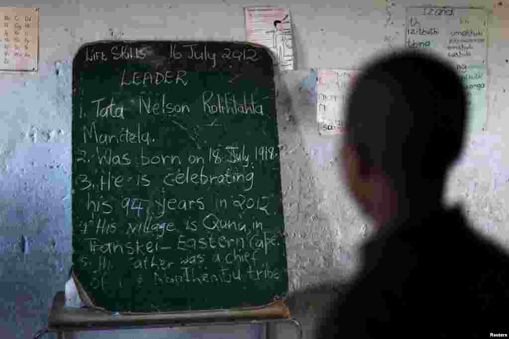 Seorang pelajar membaca sejarah mantan presiden Afrika Selatan Nelson Mandela yang tertulis di papan sebelum pembukaan perpustakaan oleh Yayasan Bill Clinton dalam perayaan Hari Mandela, di sebuah sekolah di Qunu, 17 Juli 2012.