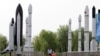 FILE - A woman walks with a child as they visit a park displaying replicas of foreign and domestic space vehicles in Beijing, China, June 26, 2016. 