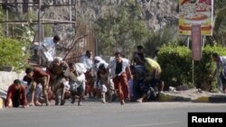 Warga mencari perlindungan saat terjadi baku tembak antara pemberontak Houthi dan milisi pendukung Presiden Hadi di kota Aden, Rabu (25/3).