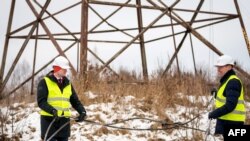 ဖြတ်တောက်လိုက်သည့် ဓာတ်အားကြိုးနှင့် အတူတွေ့ရသည့် ဥတုရာသီနှင့် စွမ်းအင်ဆိုင်ရာ လတ်ဗီးယားဝန်ကြီး Kaspars Melnis (ဝဲ)။ (၈ ဖေဖော်ဝါရီ ၂၀၂၅) (Gints Ivuskans / AFP)