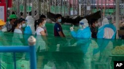 បុគ្គលិកសុខាភិបាលថៃកំពុងធ្វើតេស្តរកជំងឺកូវីដ១៩ លើពលករចំណាកស្រុកនិងក្រុមគ្រួសាររបស់ពួកគេ នៅកន្លែងធ្វើតេស្តមួយក្នុងខេត្ត Samut Sakhon ភាគខាងត្បូងទីក្រុងបាងកក ប្រទេសថៃ កាលពីថ្ងៃទី៤ ខែមករា ឆ្នាំ២០២១។