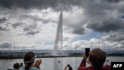 People applaud during a ceremony marking the restarting of Geneva's landmark fountain, known as Jet d'Eau, following the COVID-19 outbreak, June 11, 2020.