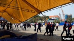 Para petugas keamanan dan pekerja berupaya merobohkan tenda yang digunakan untuk berkemah oleh para demonstran anti-pemerintah di Phnom Penh (4/1).