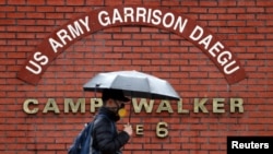 한국 대구에 위치한 주한미군기지 ‘캠프 워커’ 정문에서 마스크를 착용한 시민이 지나가고 있다. 