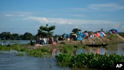 FILE- In this July 31, 2016, file photo, flood affected villagers take shelter on the elevated portion of a submerged road in Morigaon district, east of Gauhati, northeastern Assam state, India.