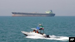 Perahu motor Garda Revolusi Iran tampak melakukan patroli di Selat Hormuz sementara sebuah kapal tanker minyak terlihat di belakang (foto: dok). 