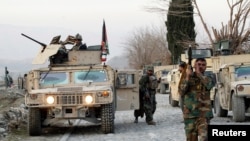 FILE - Afghan National Army soldiers inspect the site of a car bomb attack on a military base in Shirzad district of Nangarhar province, Afghanistan, Jan. 30, 2021. 