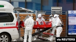 A confirmed coronavirus patient is wheeled to a hospital at Chuncheon, South Korea, Feb. 22, 2020.