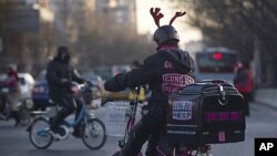 A pizza delivery man wearing a reindeer helmet rides an electric bicycle crossing a road junction in Beijing, China. Chinese leaders pledged fine-tuning to ensure stable and more balanced growth while fighting inflation, ending a top-level economic planni