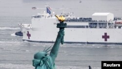 Kapal Rumah Sakit USNS Comfort melintas di depan Patung Liberty saat memasuki Pelabuhan New York di tengah wabah virus corona (COVID-19) di Kota New York, 30 Maret 2020. (Foto: Reuters)