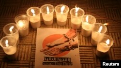 FILE - Lit candles are placed by activists around a placard during a vigil in solidarity with the detainees in Syrian prisons at Aleppo's Salaheddine neighborhood, Jan. 26, 2015. 