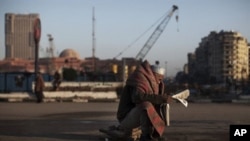 An Egyptian anti government demonstrator reads a newspaper after waking up from a night spent inTahrir Square, February 8, 2011