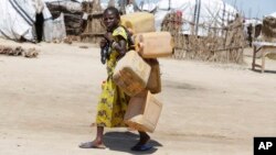 In this photo taken Sunday Aug. 28, 2016 a girl displaced by Islamist Extremists carries empty plastic containers at a camp Maiduguri, Nigeria.