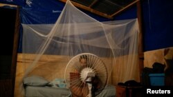 Karla Gerrido works on her computer in front of a fan that works with electricity from a generator, at her house, which was partially destroyed by Hurricane Maria in Canovanas, Puerto Rico, Dec. 11, 2017.