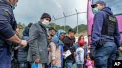 Migrants wait to board on buses outside Moria camp on their way to the port of Mytilene, on the northeastern Aegean island of Lesbos, Greece, May 3, 2020.