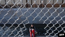 Porodica migranata iz Kolumbije penje se kroz ogradu kanala nakon što je prešla kroz rupu u zidu granice između SAD i Meksika u El Pasu, Teksas, 19. decembra 2022.