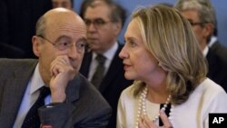 Secretary of State Hillary Rodham Clinton talks with France's Foreign Minister Alain Juppe during a meeting on Syria, April 19, 2012, in Paris