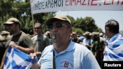 Municipal police hold Greek flags as they protest outside parliament during a rally against the public sector reforms in Athens, July 8, 2013. 