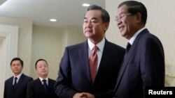 Chinese Foreign Minister Wang Yi (2nd R), shakes hands with Cambodia's Prime Minister Hun Sen before a meeting in Phnom Penh, Aug. 21, 2013. 