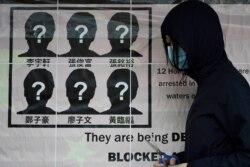 FILE - A university student puts up a poster to demand the release of the 12 Hong Kong activists detained at sea by Chinese authorities, at a "Lennon wall" in the University of Hong Kong, Sept. 29, 2020.