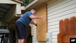 A man boards up the windows to his home in advance of Tropical Storm Helene, expected to make landfall as a hurricane, in Ochlockonee Bay, Florida, Sept. 25, 2024.